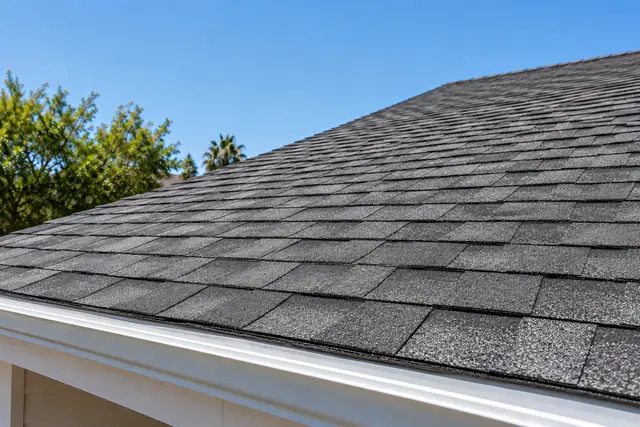 AI-generated illustration: layered charcoal asphalt shingles on a traditional ranch home